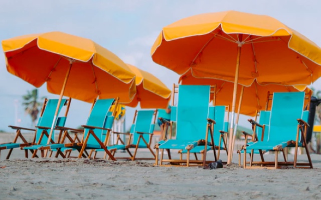 A group of blue chairs with orange umbrellas set up on a beach