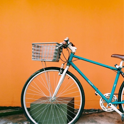 A blue bicycle with a basket, against an orange wall